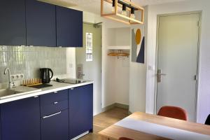 a kitchen with blue cabinets and a wooden table at Cit'hotel Design Booking Evry Saint-Germain-lès-Corbeil Sénart in Saint-Germain-lès-Corbeil