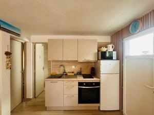 a small kitchen with white cabinets and a refrigerator at Bas de Chalet Santa Giulia in Gruissan