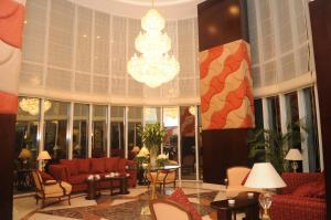a living room with red couches and a chandelier at Kingsgate Hotel Doha by Millennium Hotels in Doha