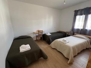 a room with two beds and a table and a window at Casa do Belé in Faro