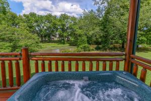 a hot tub on the back of a porch with trees at River Cabin in Pigeon Forge