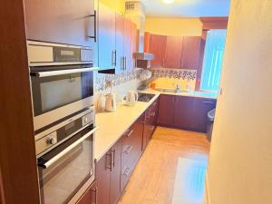 a kitchen with wooden cabinets and stainless steel appliances at Pokoje noclegowe KASZTEL - Łowisko in Łowisko