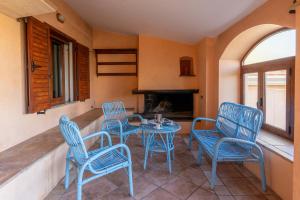 a patio with blue chairs and a table and a fireplace at Villa Sa Marina con piscina in Bari Sardo
