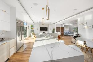 une cuisine et un salon avec une grande table blanche dans l'établissement Luxury 5BR Smart Home Near JFK with Gym, Theater & BBQ, à Valley Stream