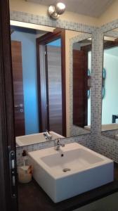 baño con lavabo blanco y 2 espejos en Le Case Di Bacco, en Santa Venerina