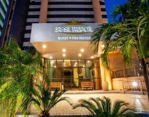 a hotel with palm trees in front of a building at Hotel Brasil PREMIUM 604 in Fortaleza