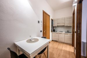 una pequeña cocina con mesa blanca y sillas en Emilia Studios 3, en Módena