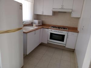 a kitchen with white cabinets and a white stove top oven at Fresnos 14 Queretaro in Mendiola