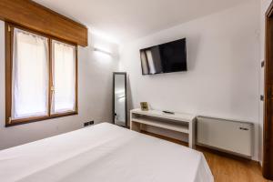 a bedroom with a white bed and a tv on the wall at Emilia Studios 4 in Modena