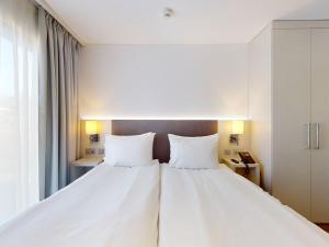 Voodi või voodid majutusasutuse Nonanteneuf appart hōtel Vevey - contactless check-in toas