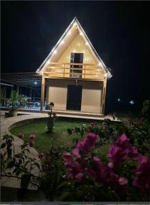 a small house with a yard with purple flowers at Chalé da Lourdes in Santarém