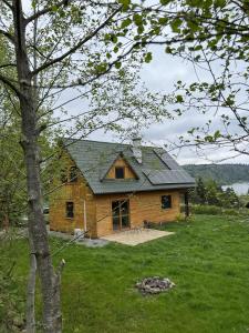 une maison en rondins avec un toit vert dans un champ dans l'établissement Borówka, à Zawóz 19 autres photos