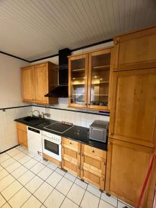 a kitchen with wooden cabinets and a stove top oven at Ferienhaus in ruhiger Lage mit 2 Bädern in Neumünster