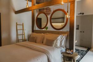 a bedroom with a large bed with two mirrors on the wall at Anacardier Privé Hotel in Atins
