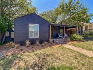 ein schwarzes Haus mit einer Veranda und einem Rasen in der Unterkunft Fort Worth Cottage Retreat in Fort Worth