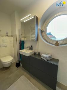 Un baño con lavabo, inodoro y ventana. en Haus Poseidon Ferienwohnung 4 1, en Wangerooge 24 fotos más