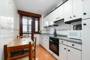 a kitchen with white cabinets and a wooden table at Con parking y para 6 huéspedes by CABANA Rentals in Cangas de Morrazo