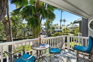 a balcony with a table and chairs and palm trees at Kokua at Kona Bay Estates in Kailua-Kona