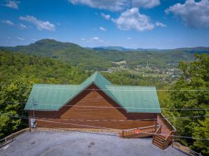 a house with a green roof with mountains in the background at Getaway Mountain Lodge in Sevierville