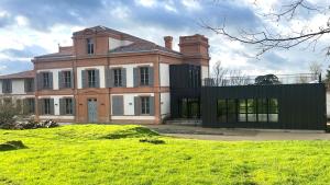 a large house on a grassy field in front at Domaine de Pousiniès in Saint-Étienne-de-Tulmont