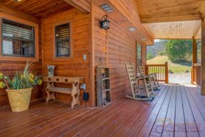 a cabin with a wooden deck with a bench and a table at Bear Run in Sevierville