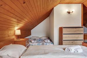 deux lits dans une chambre avec un plafond en bois dans l'établissement Urban Escape Cottage, à Ljutomer 16 autres photos