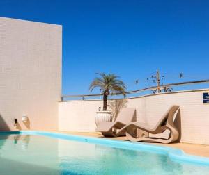 a swimming pool with chairs next to a building at Rapport Hotel in Juazeiro
