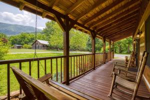 - une terrasse couverte avec 2 chaises et une balançoire dans l'établissement 4 Paws Lodge, à Sevierville