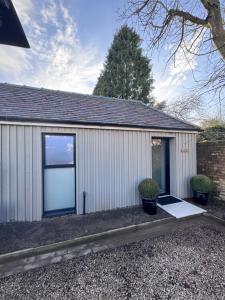 a white garage with a door and two plants at Tithe Cottage in Tamworth