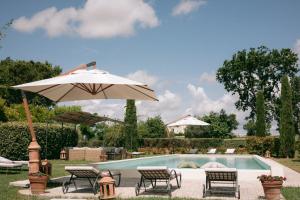 ein Pool mit Stühlen und einem Sonnenschirm neben einem Pool in der Unterkunft La Monteduccia in Ostra Vetere