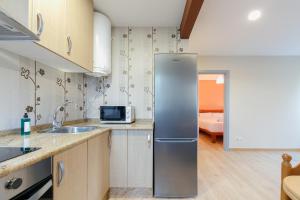 a kitchen with a stainless steel refrigerator and a bedroom at Cómodo y económico by CABANA Rentals in Vigo