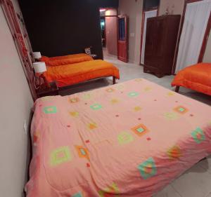 a bedroom with two beds with orange and green sheets at Cabañas Mallma in Tilcara +7 photos