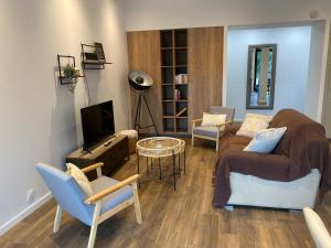 a living room with a couch and a tv at Les Ecureuils in Pougues-les-Eaux