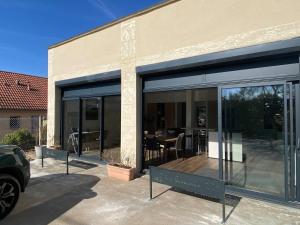 a building with large glass doors with a table in it at Les Ecureuils in Pougues-les-Eaux