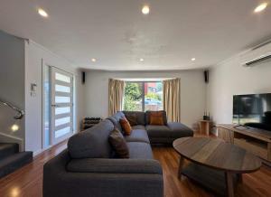 a living room with a couch and a table at Tasman Tranquility - close to City & Airport in Derwent Park