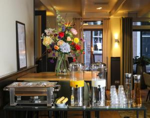 a table with a vase of flowers in a room at Hotel Aalsmeer in Aalsmeer +18 photos