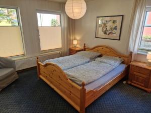a bedroom with a wooden bed and two windows at Ruhige Ferienwohnung mit Privatparkplatz in Sagard