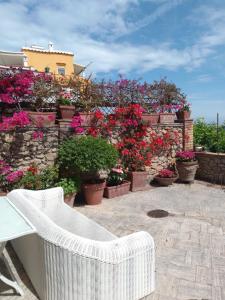un banco blanco de mimbre sentado en un patio con flores en Cri Cri, en Marina Grande