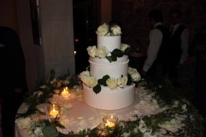 a three tiered wedding cake with white roses on it at Tenuta San Pietro Luxury Hotel in Lucca +44 photos