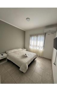 a white bedroom with a bed and a window at Departamento zafiro con cochera a 100mts del Shopping y el Puerto in Santa Fe