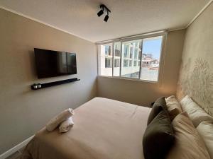 a person laying on a bed in a room with a tv at Encantador e Iluminado Departamento, Ñuñoa in Santiago