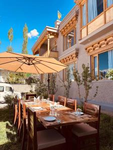 a long wooden table with chairs and an umbrella at The Shava Ladakh in Leh