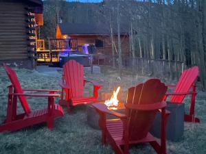 two red chairs and a fire pit in a yard at Cozy Mountain Cabin W Hot Tub Breathtaking Views in Alma