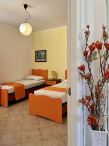 een kamer met 2 bedden en een vaas met bloemen bij Yellow Beachfront house 60 m by Salento Prime in Marina di Pescoluse