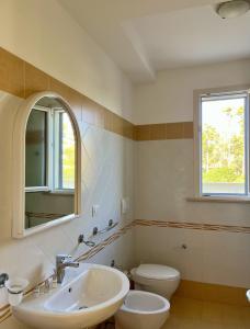 een badkamer met een wastafel, een toilet en een spiegel bij Yellow Beachfront house 60 m by Salento Prime in Marina di Pescoluse