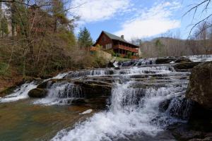 a waterfall in front of a house next to a river at Creekside Lodge in Sevierville