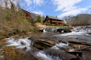 a river in front of a house with a waterfall at Creekside Lodge in Sevierville