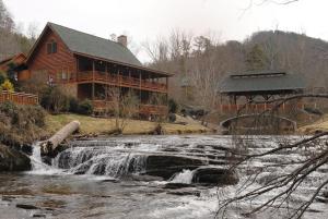 a log cabin next to a river with a waterfall at Creekside Lodge in Sevierville