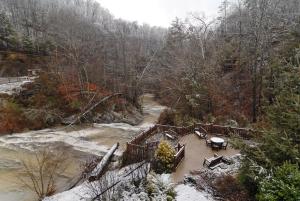 a bridge over a river with snow on the ground at Creekside Lodge in Sevierville