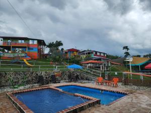 a swimming pool with orange chairs and a playground at Alojamiento el jardin in Filandia